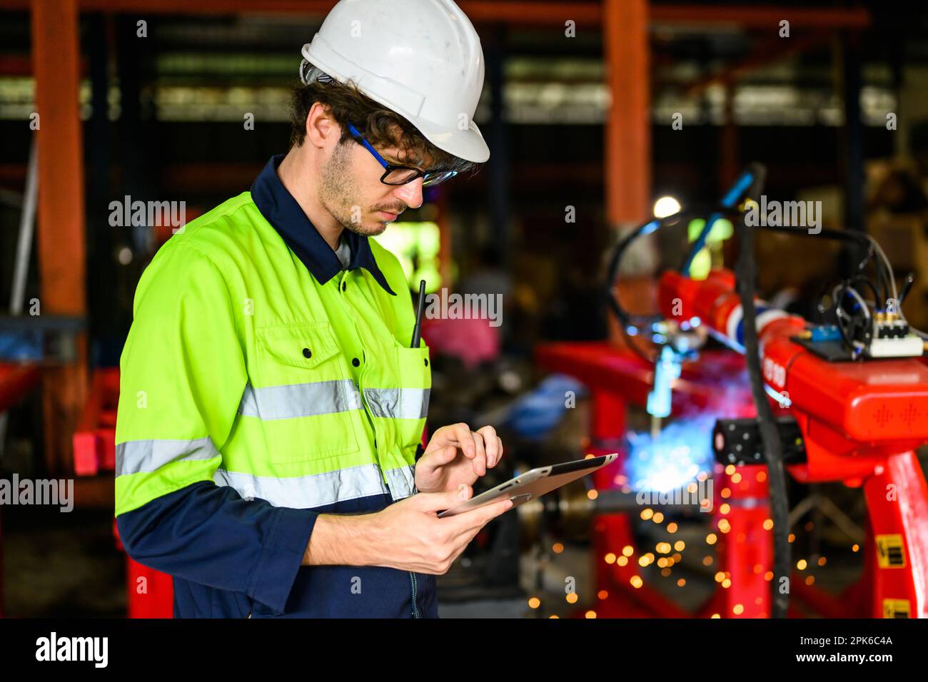 Young mechanical technician using tablet checking machine at warehouse Stock Photo