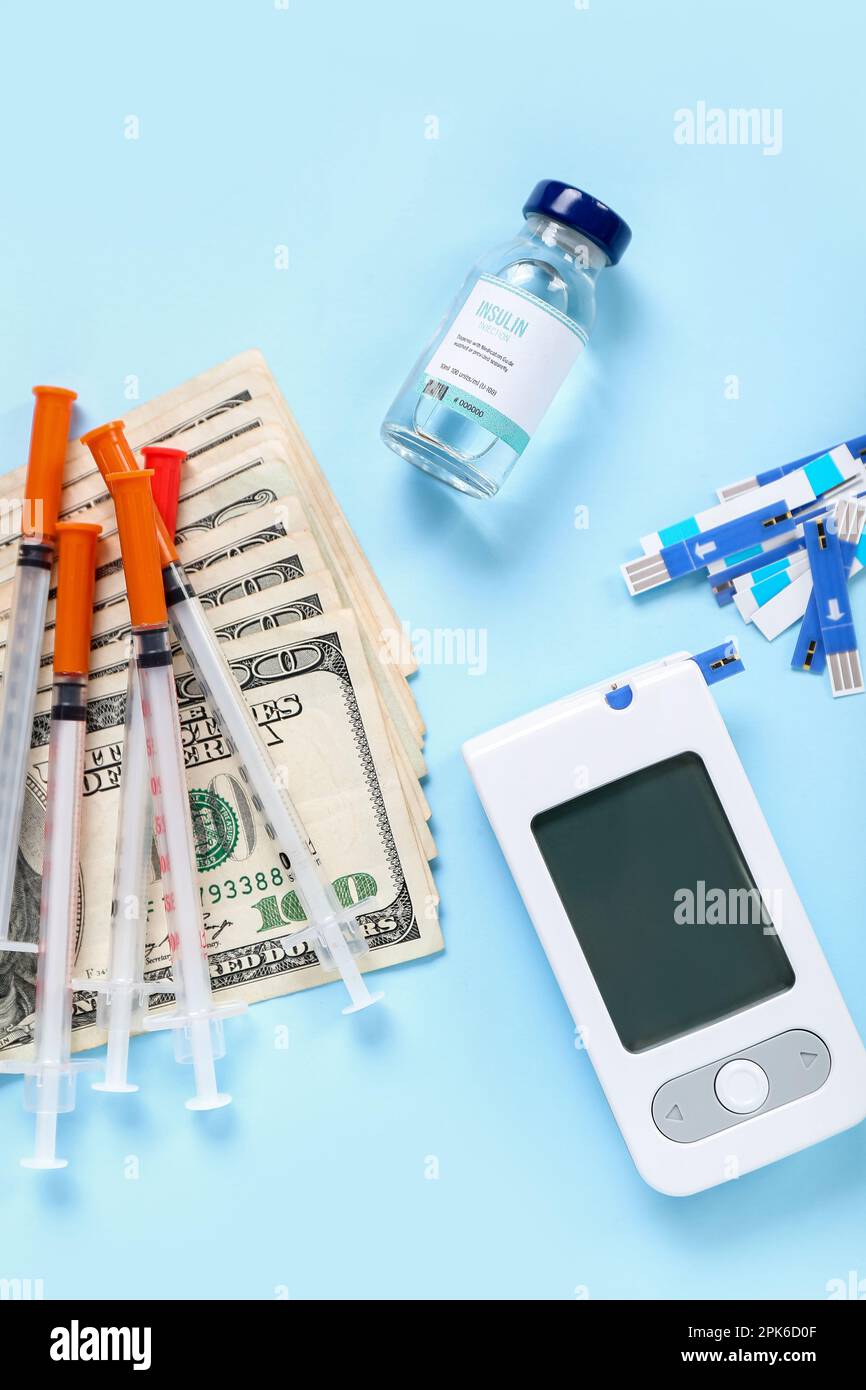 Insulin with lancet pens, syringes and money on blue