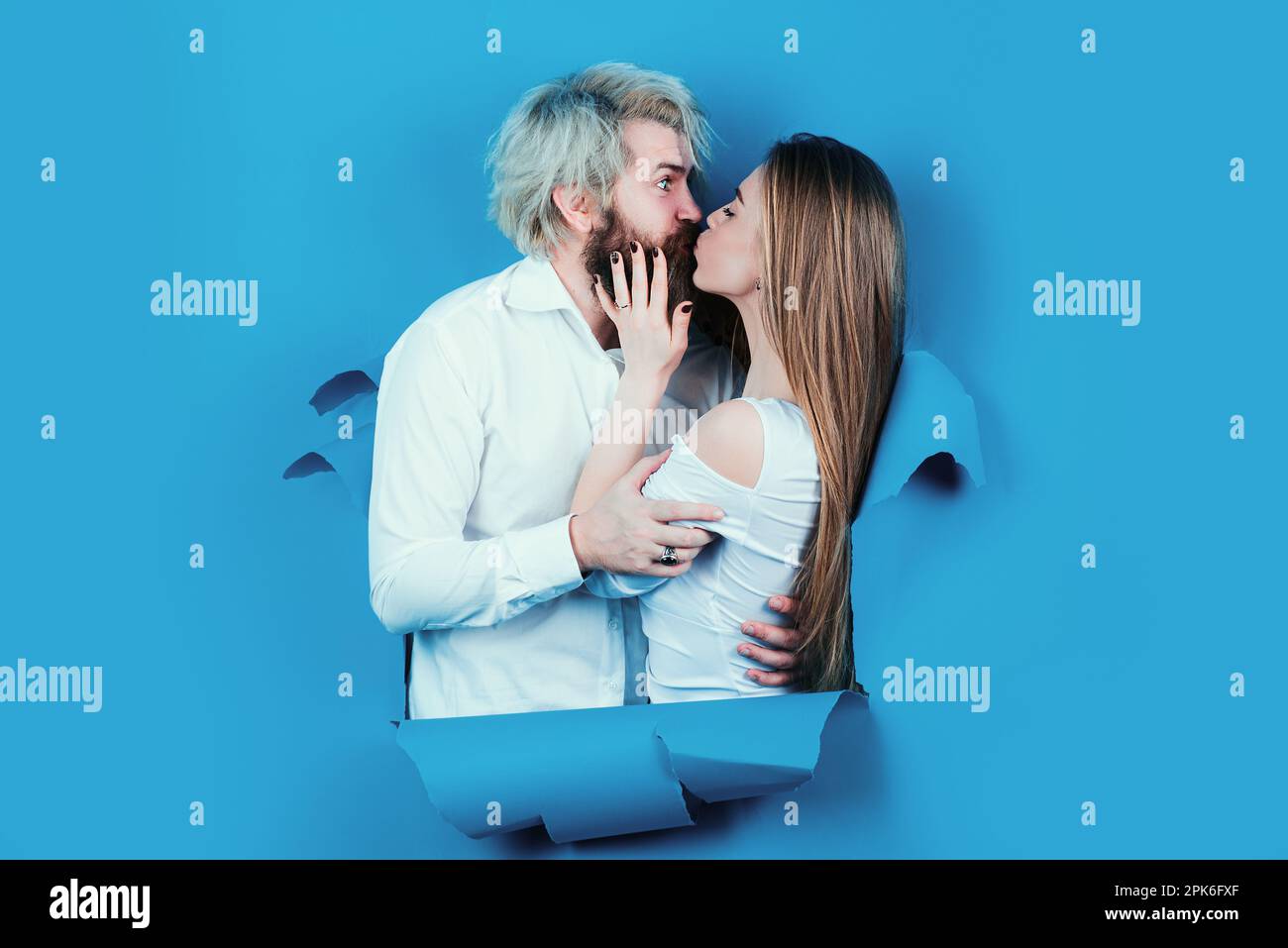 Couple in hole paper. Discount and sale. Kissed couple of bearded man and happy woman making hole in paper kiss through hole. Advertising board, blue Stock Photo