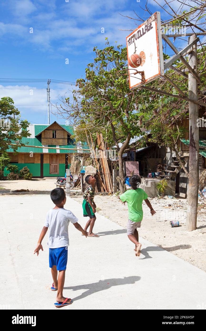 Boys playing basketball, a traditional house in the back, Boracay Ati Community Development Complex, Barangay Manoc-Manoc, Boracay Island, Visayas Stock Photo