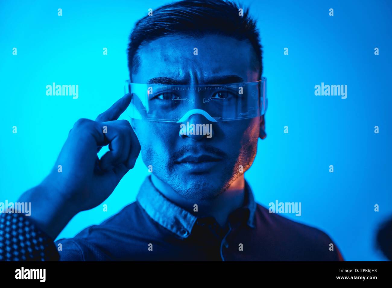 Portrait of young chinese man with neon glasses with a blue light, futuristic concept, technology of cyber humans Stock Photo