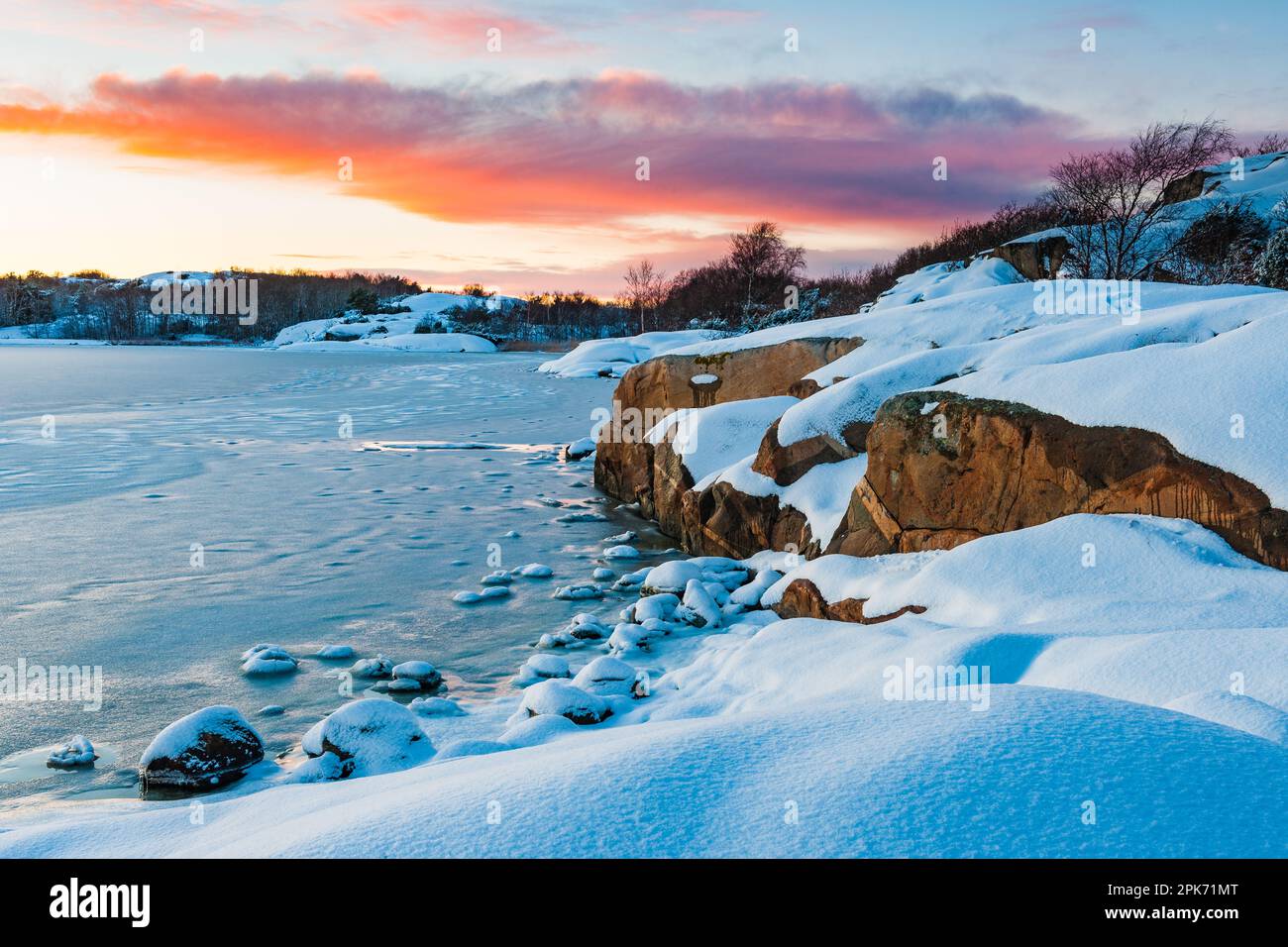A stunning winter wonderland of frozen sea, snow-capped land and an icy sky at sunset; a breathtaking reminder of the beauty in nature. Stock Photo