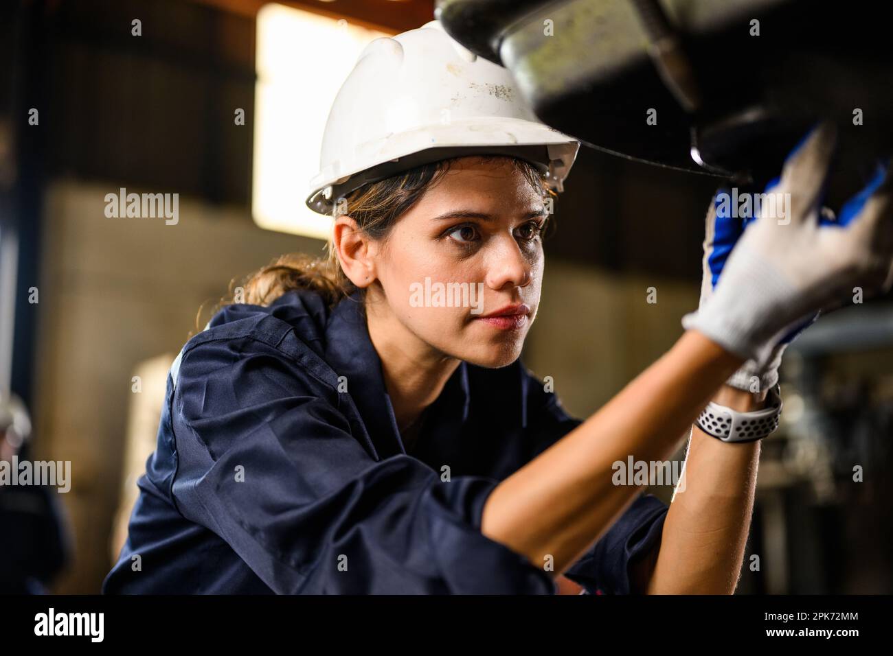 Portrait of female mechanical engineer repairing engine machine at ...