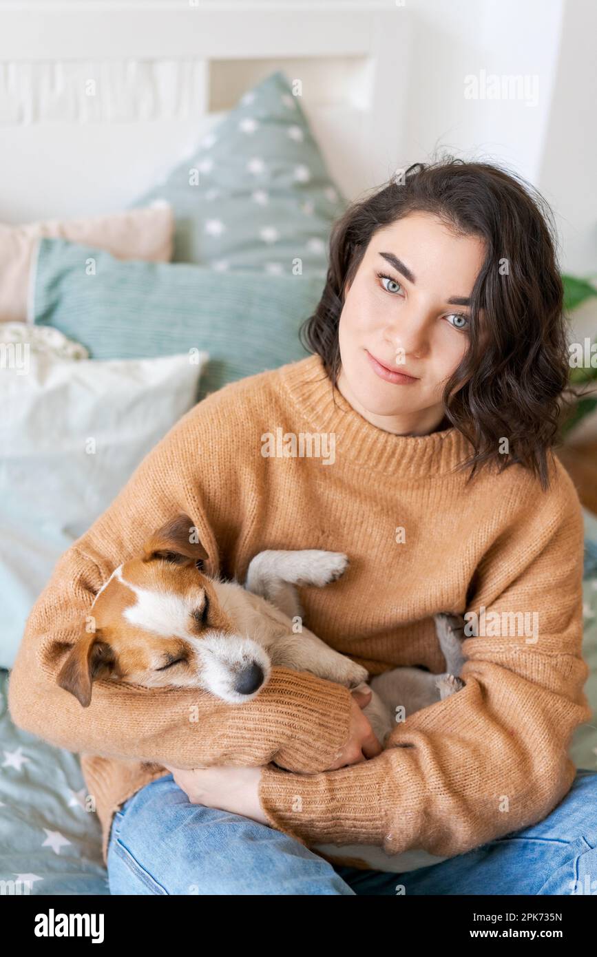 Picture of Woman hugs cute little dog lying in her arms at home. Close-up. Trust ...