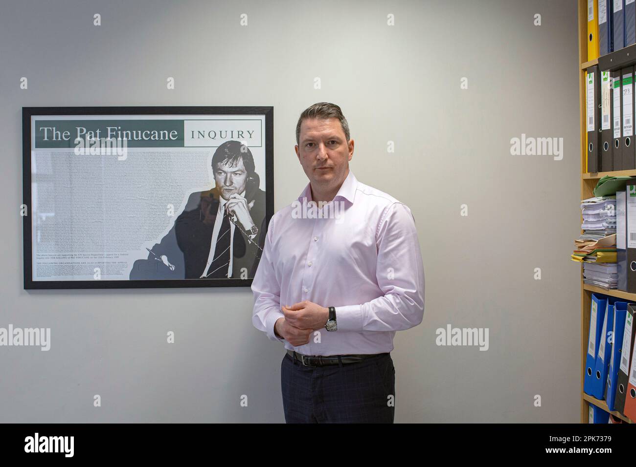 John Finucane , Irish lawyer and Sinn Féin politician in front of a  photo of his father lawyer Pat Finucane, who was murdered in 1989. Stock Photo
