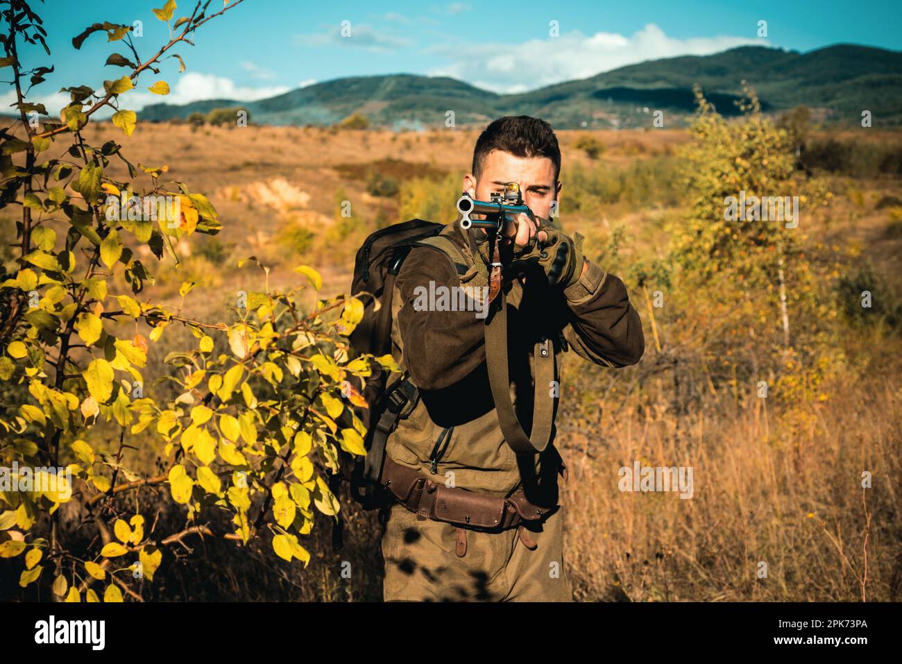 Hunter with Powerful Rifle with Scope Spotting Animals. Hunter with shotgun gun on hunt. Track down. Deer hunt. Stock Photo