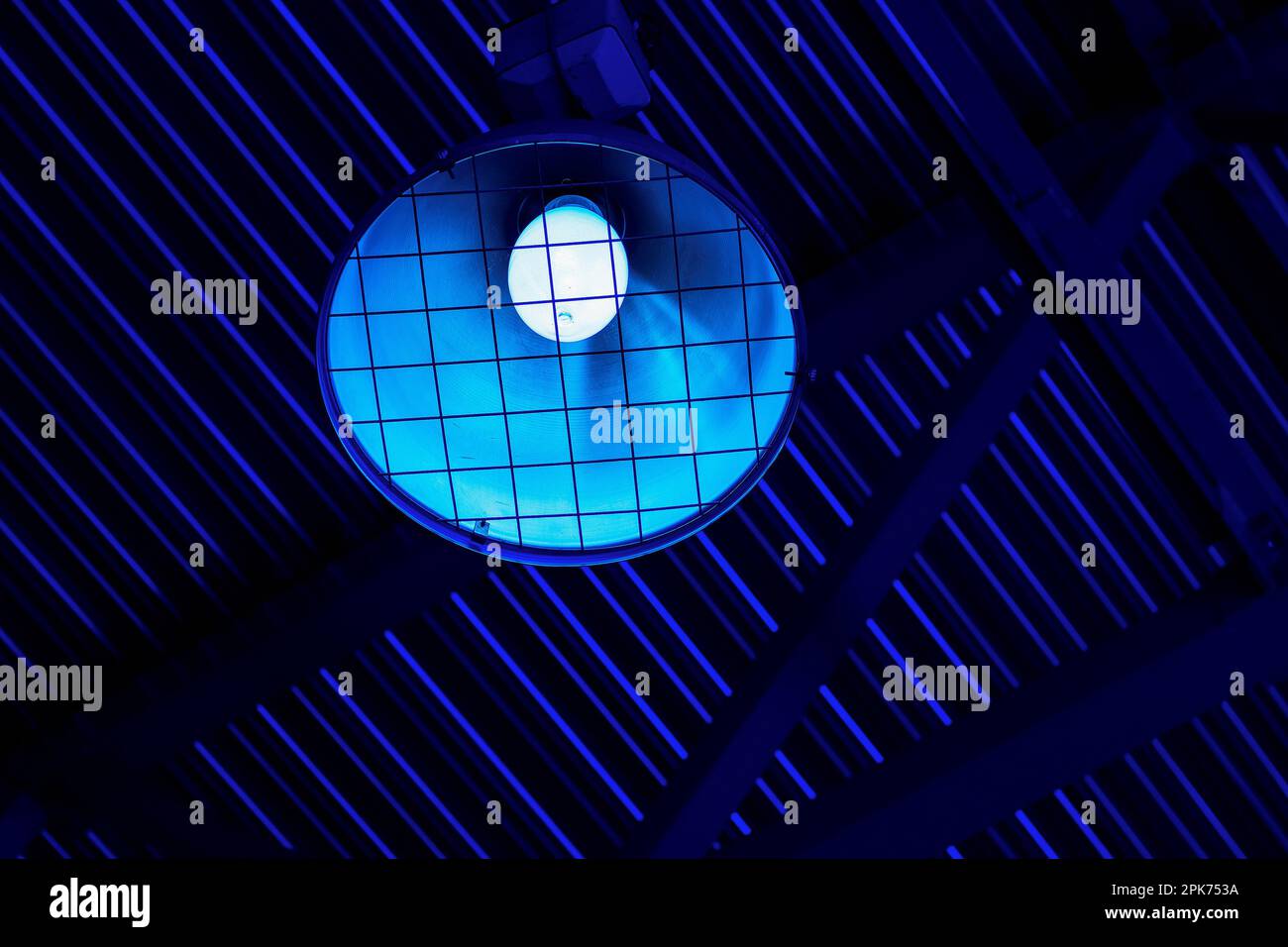 Lampshade with lamp hangs under roof of industrial room inside. Gloomy