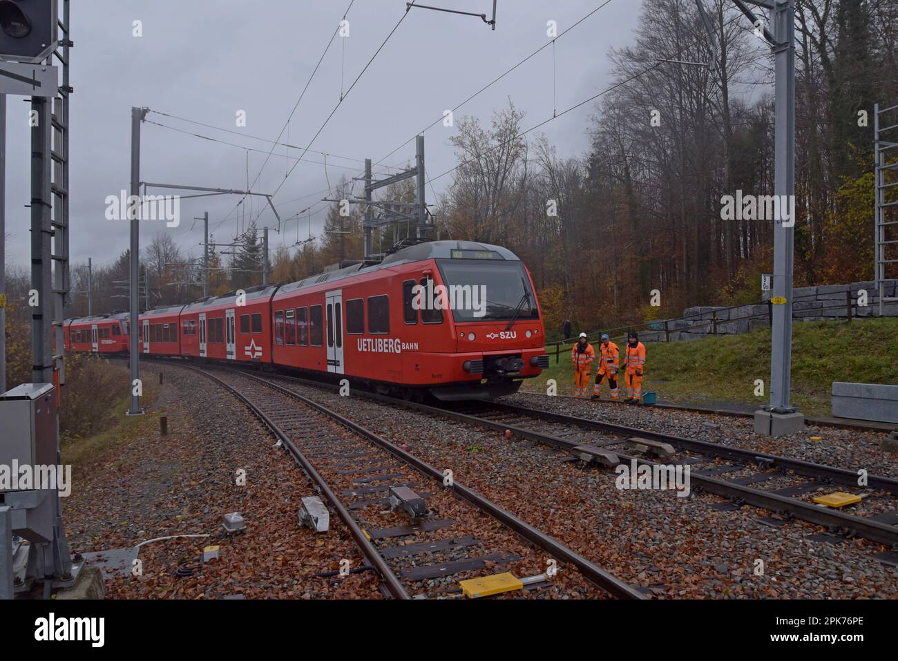 Track maintenance workers wait as a Uetliberg mountain railway train passes them approaching Uetliberg station, Zurich, Switzerland Stock Photo