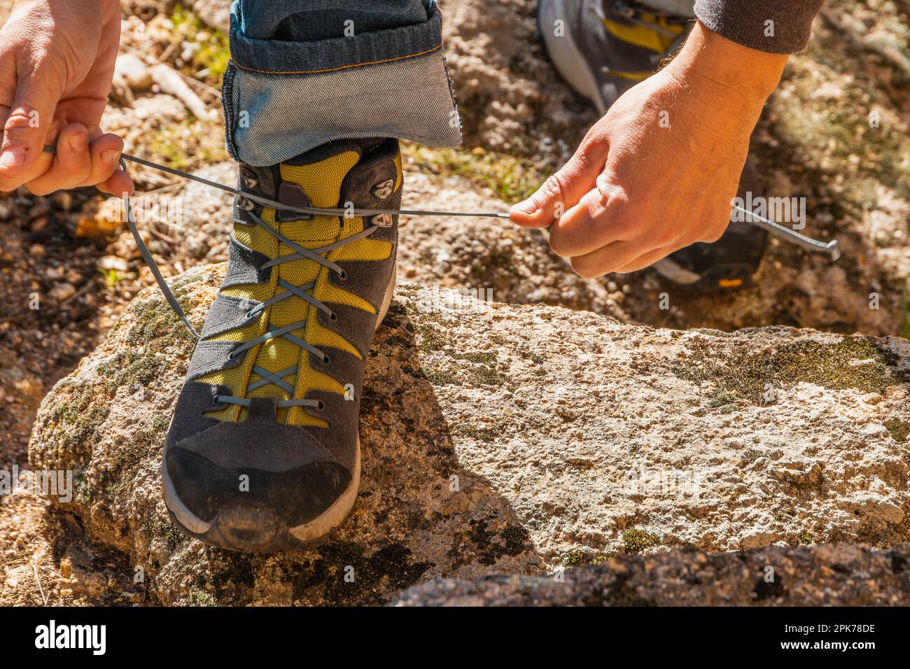 Close up of an unrecognizable man tying shoe laces of his trekking boots on a granite rock Stock Photo