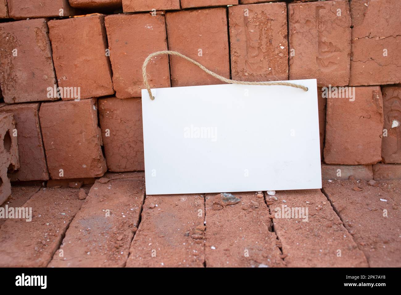 pile of stacked red bricks with white hanging picture sign with empty