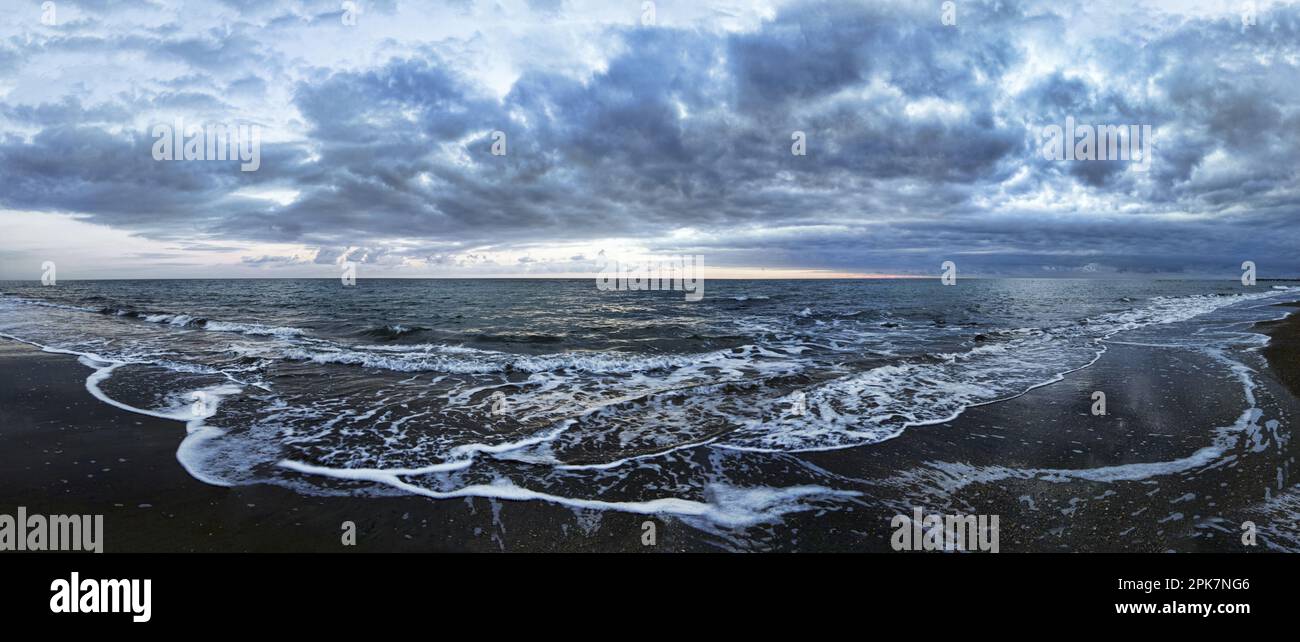 Bad weather at blue hour seascape view of  and threatening sky on coast with rough and foamy sea and stormy sky with nimbostratus clouds. Stock Photo