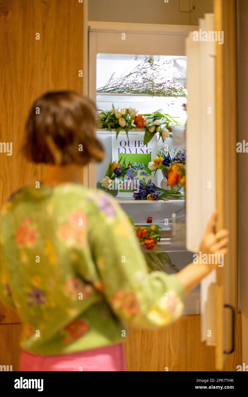 Woman opens fridge filled with fresh flowers at home Stock Photo Alamy