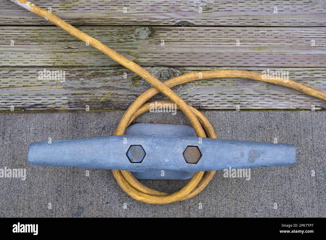 A power cable wraped around a metal nautical cleat on the dock, quayside Stock Photo