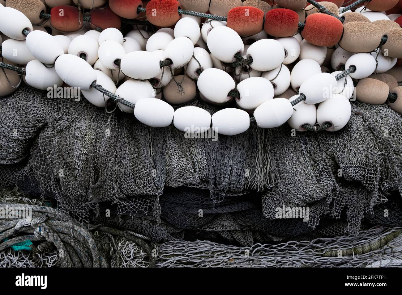 A pile of commercial fishing nets on a quay, white and red plastic floats  and nets and ropes Stock Photo - Alamy