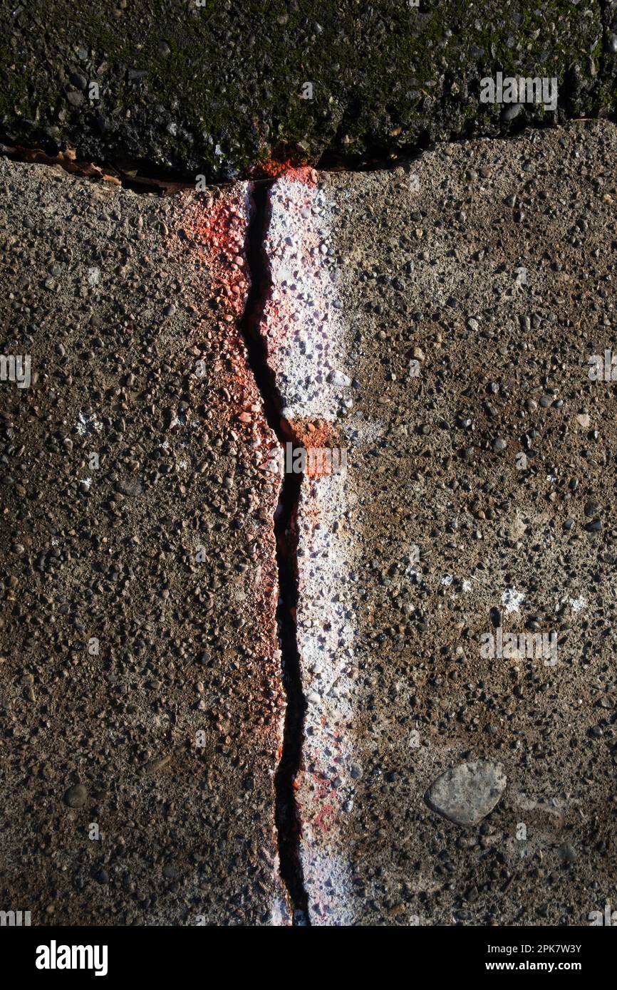 A crack in the paving, highlighted by white paint. Stock Photo