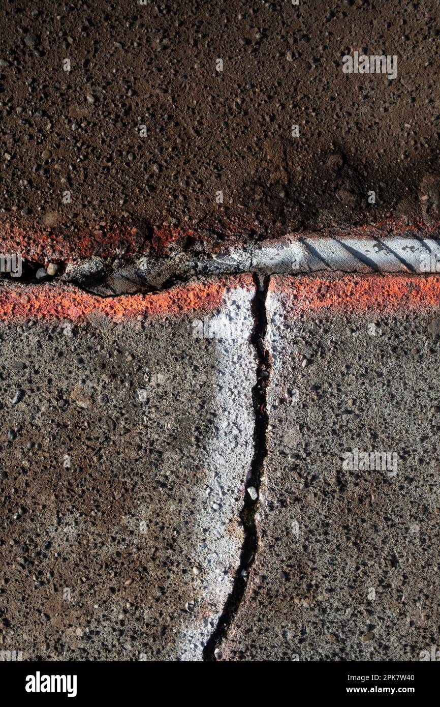 A crack in the paving, highlighted by white paint. Stock Photo