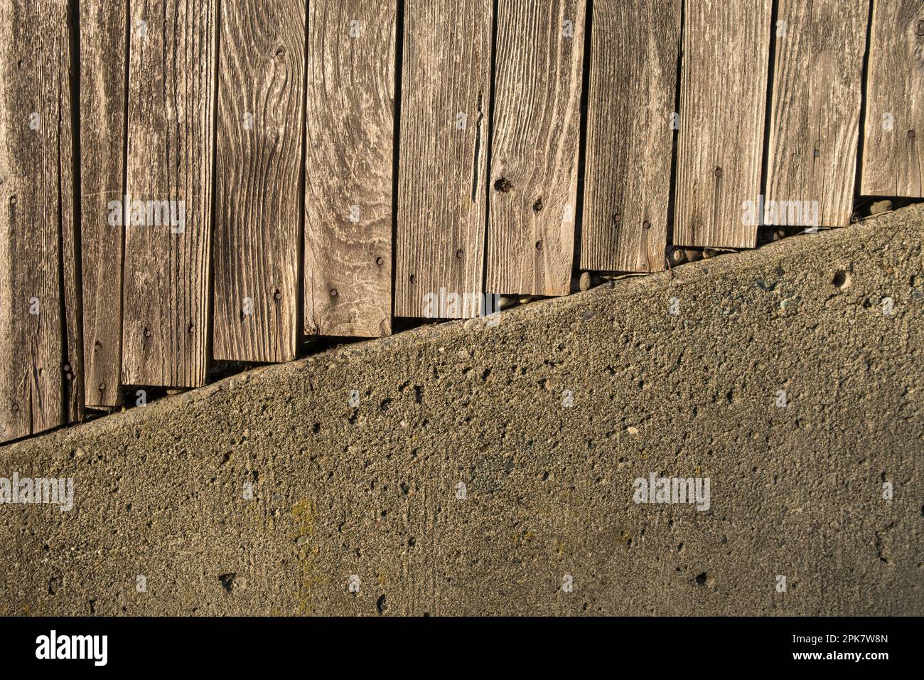 Planks of a wooden fence and concrete wall. Stock Photo