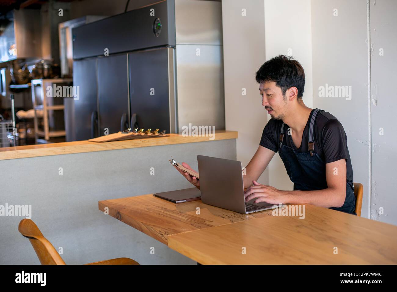 A man seated at a table using a laptop computer, owner and manager of a small restaurant. Stock Photo