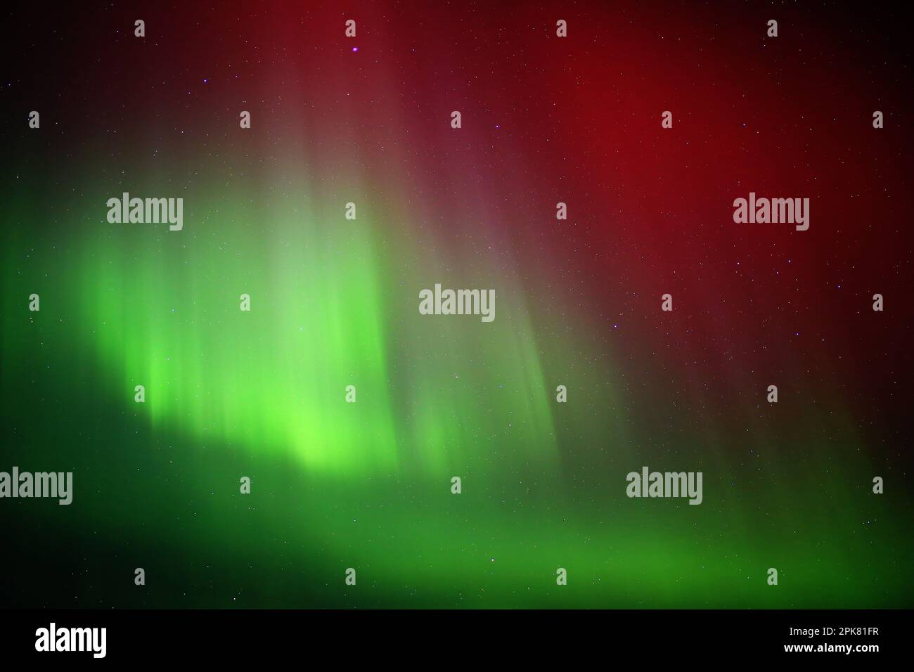 Red and green aurora borealis on starry sky. Stock Photo