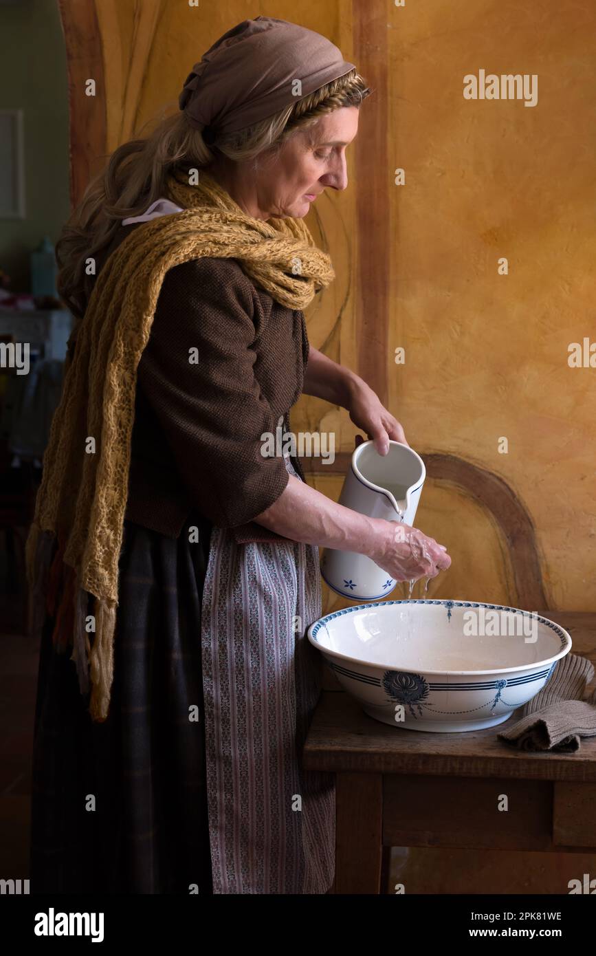 Woman in peasant renaissance costume washing her hands in an antique basin Stock Photo