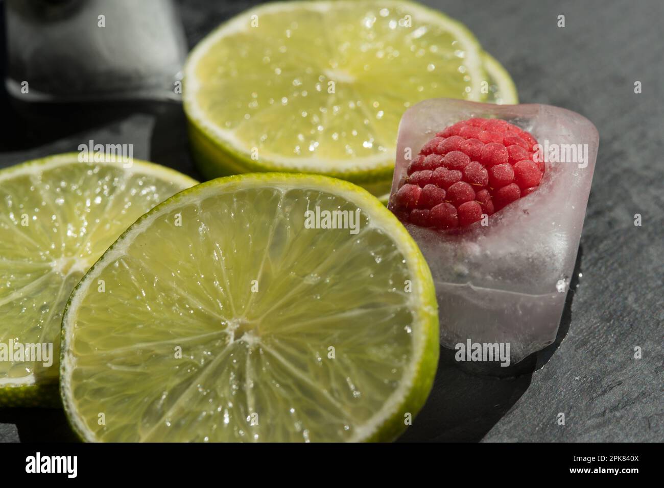 un bel mix di frutta ghiacciata, cubetti di ghiaccio con fette di lime, lamponi e mirtilli. Stock Photo