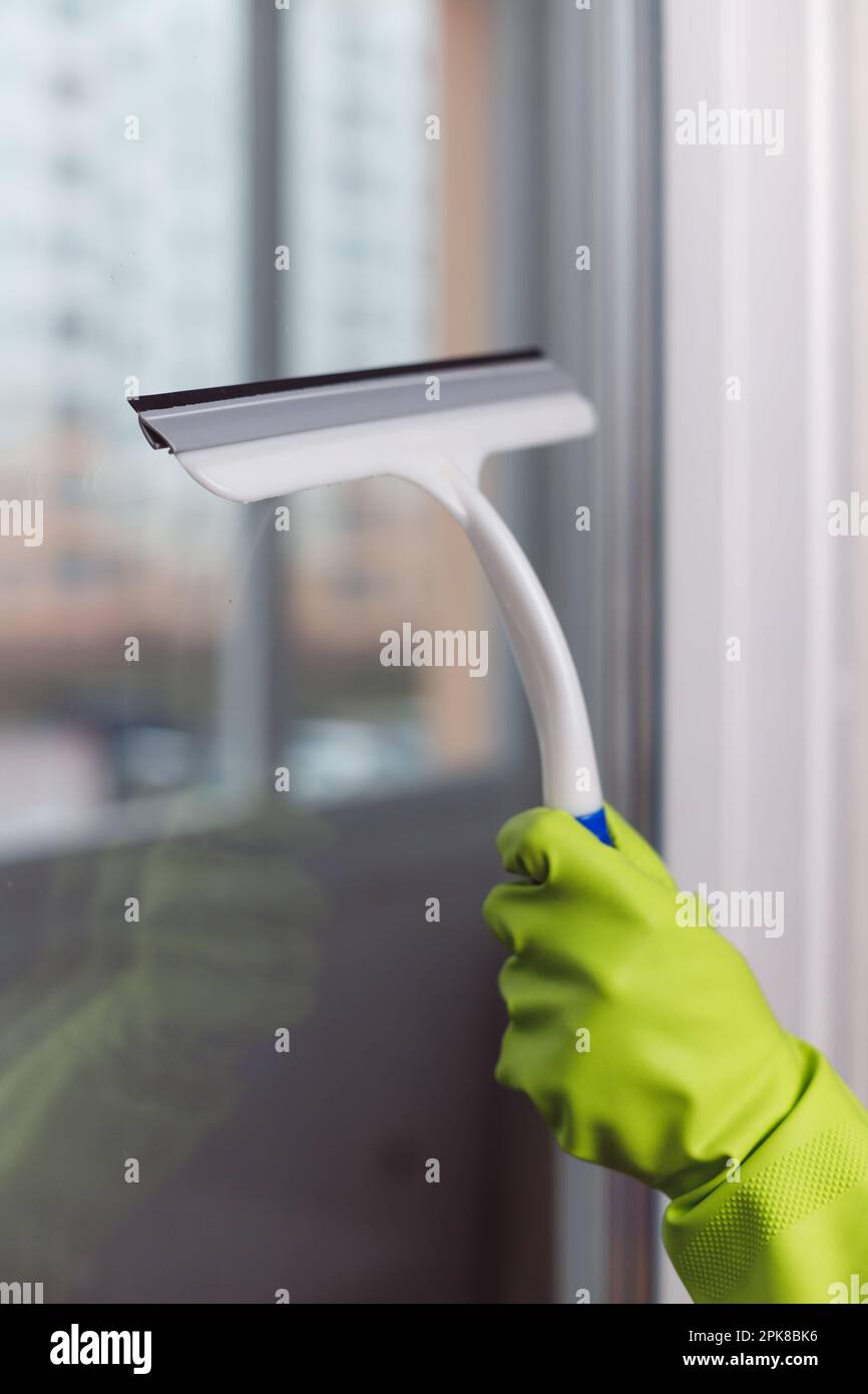 Hand in Green Glove Wiping Window with Window Wiper. Professional