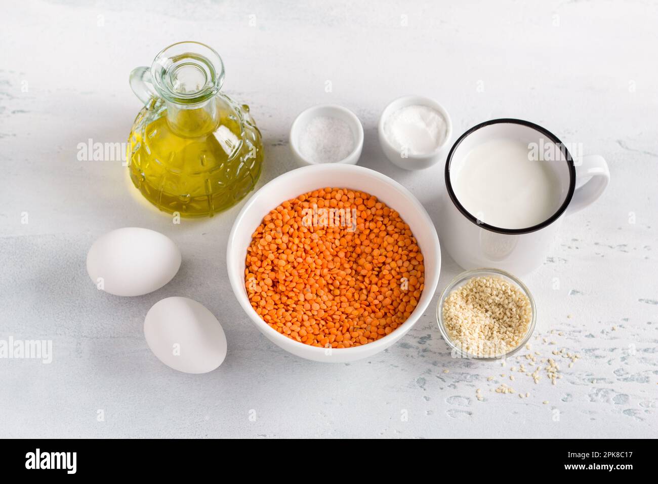 Ingredients for a vegetarian dish, lentil bread, pancakes, casseroles: red lentils, yogurt, olive oil, eggs, sesame seeds, baking powder and salt on a Stock Photo