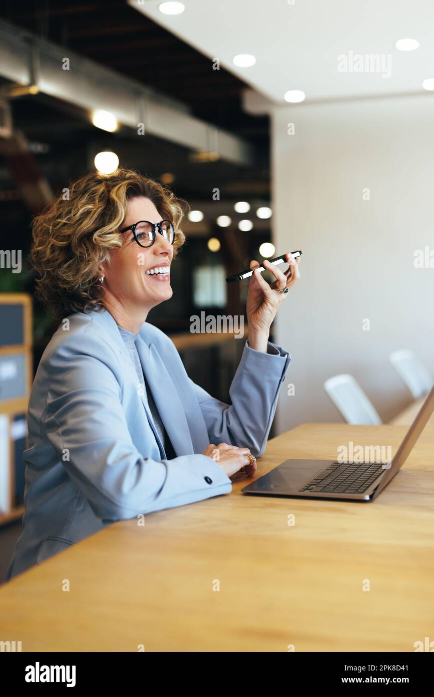 Happy business woman having a phone call conversation in an office. Professional woman speaking with her associates on a mobile phone. Woman sitting w Stock Photo