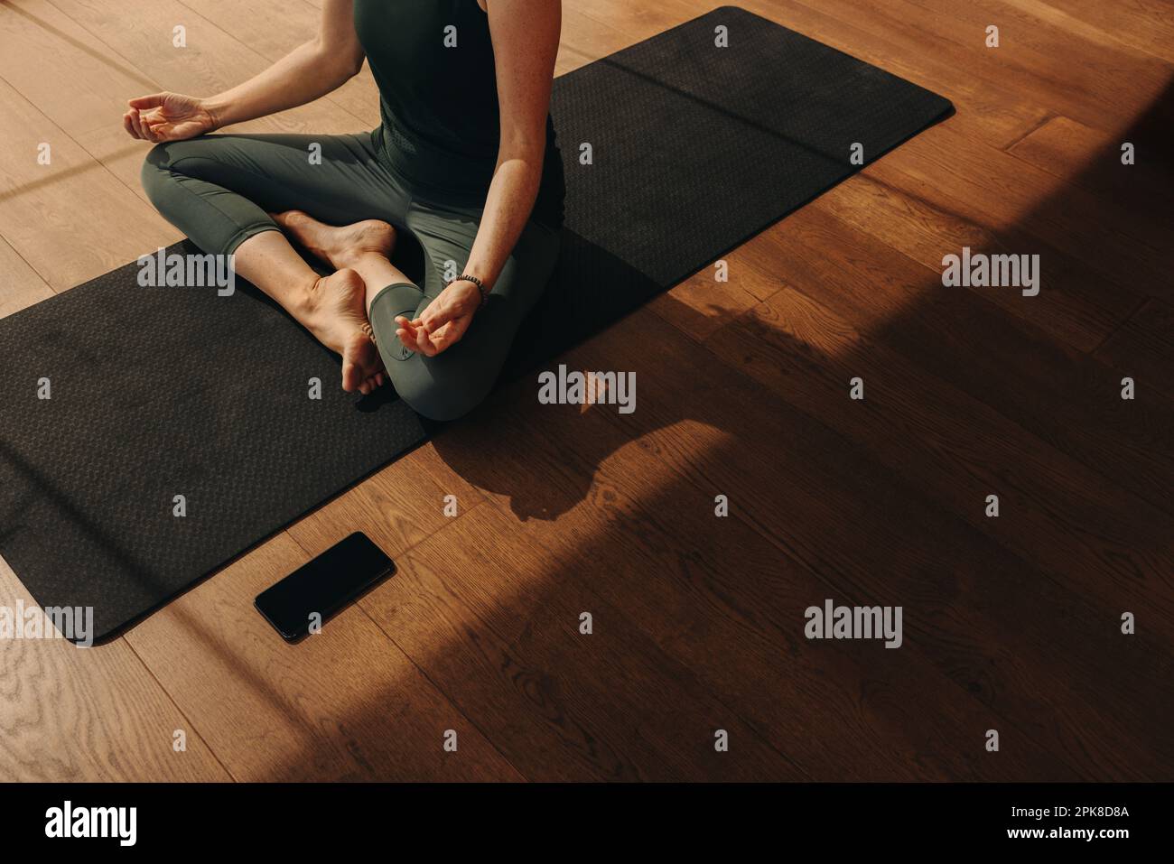 High angle view of a senior woman meditating and practicing hatha yoga. Unrecognizable woman doing a breathing exercise while sitting in easy pose. Wo Stock Photo