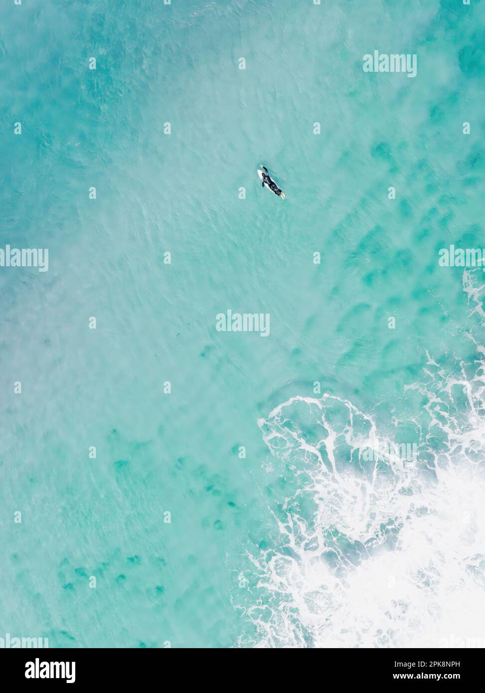 View from above, stunning aerial view of a person surfing on a turquoise ocean. Fuerteventura, Canary Islands, Spain. Stock Photo