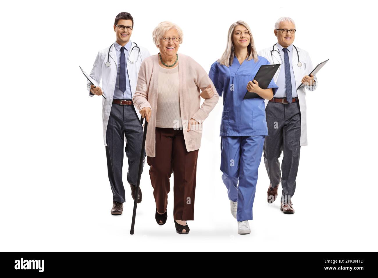 Full length portrait of a young female nurse and male doctors walking with an elderly female patient isolated on white background Stock Photo