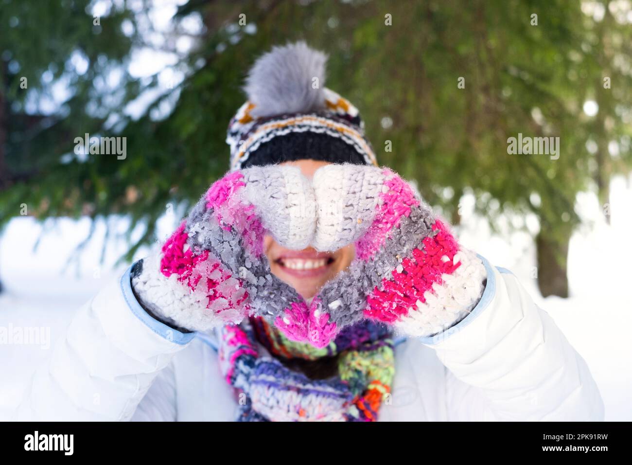 Happiness and joyful outdoor leisure activity people. One woman smiling and doing heart sign gesture with hands wearing warm knitted wool gloves in snow winter holiday vacation travel day concept Stock Photo