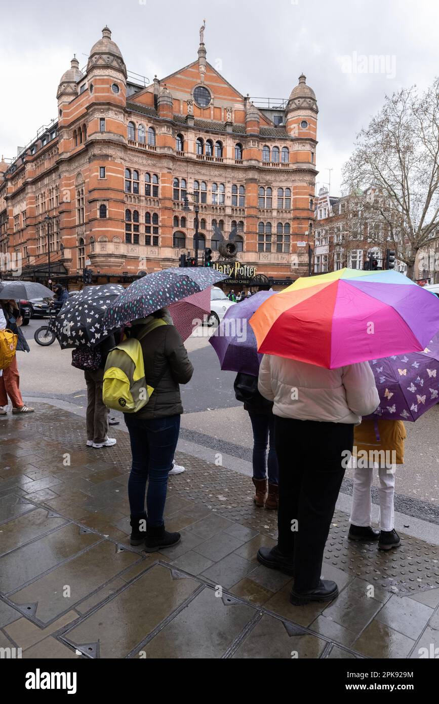 Tourists in central London take shelter underneath umbrellas across the road from The Palace