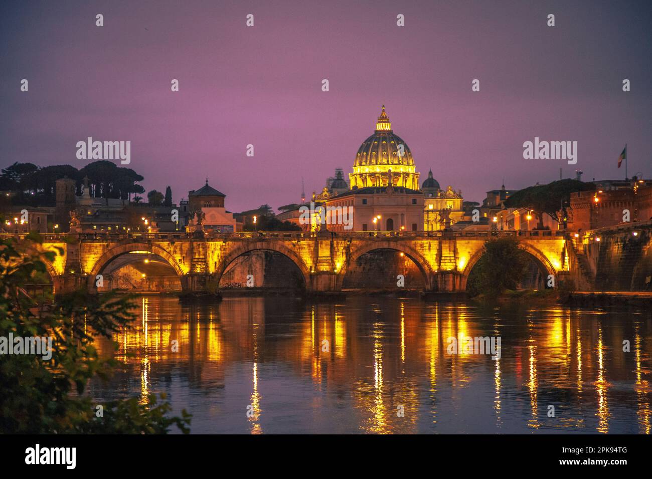 View from the Ponte Umberto I bridge over the Angel Bridge / Pons Aelius / Ponte Sant'Angelo bridge to the Vatican and St. Peter's Basilica in the evening Stock Photo