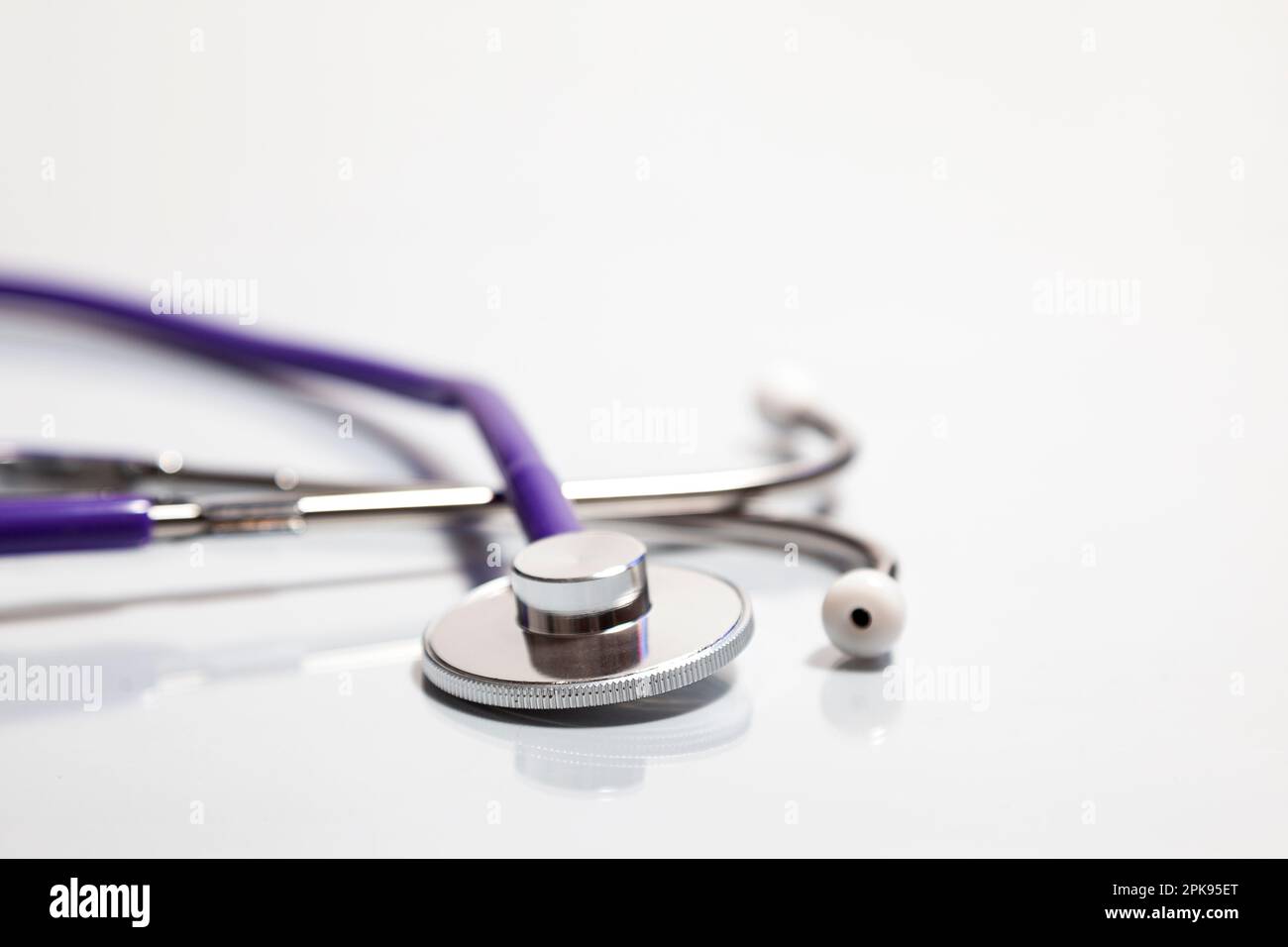 Closeup of a stethoscope's bell over a white surface where is