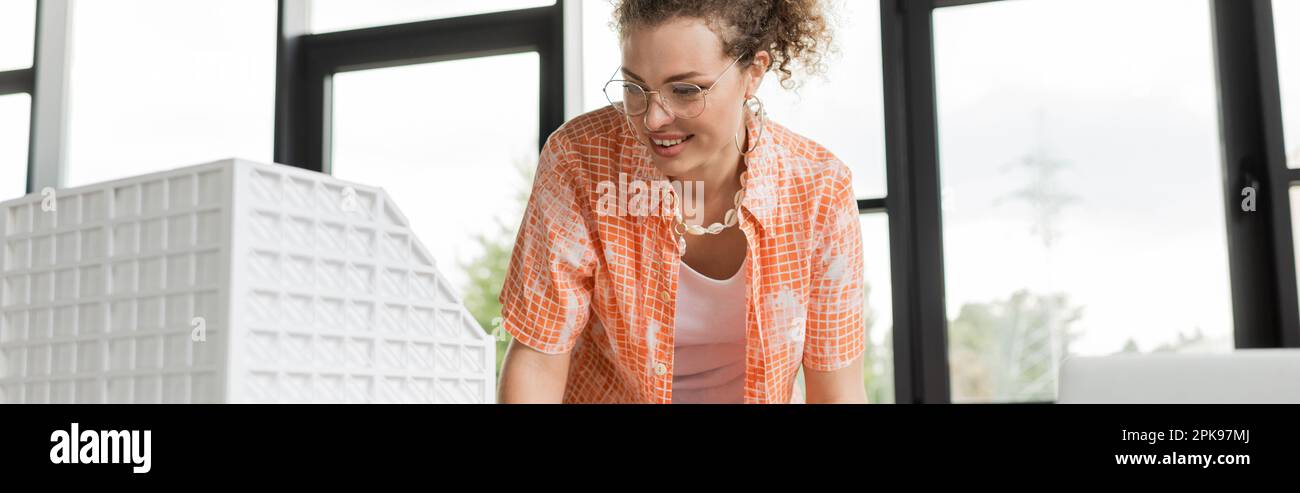 cheerful designer looking at architecture model in modern office, banner,stock image Stock Photo