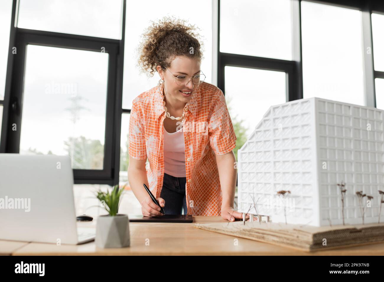 cheerful designer looking at architecture model while using graphic tablet in office,stock image Stock Photo