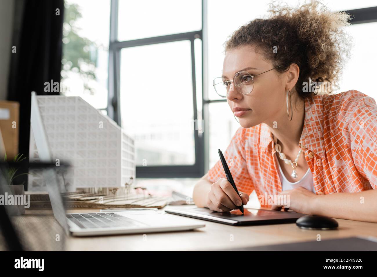 focused architectural designer using graphic tablet and looking at laptop while working in office,stock image Stock Photo