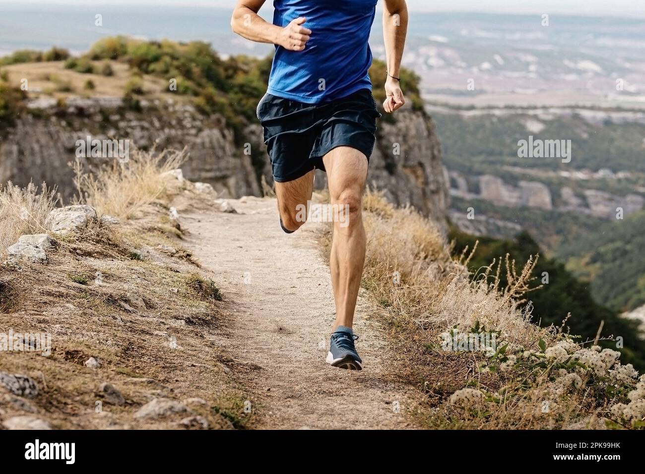 rangy male runner run on mountain trail, muscular legs man jogger