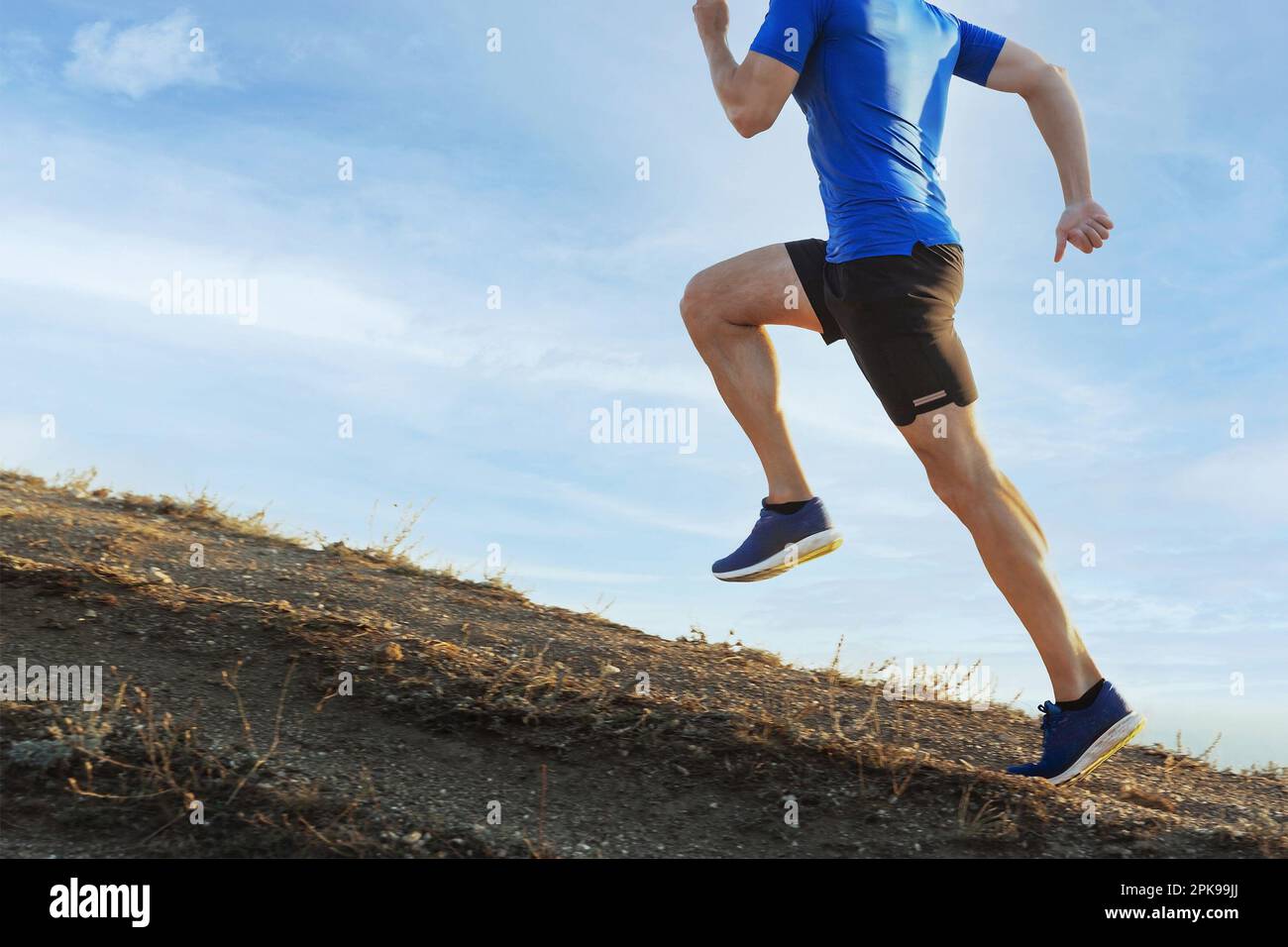 male runner run steep mountain climb on trail in blue sky background ...