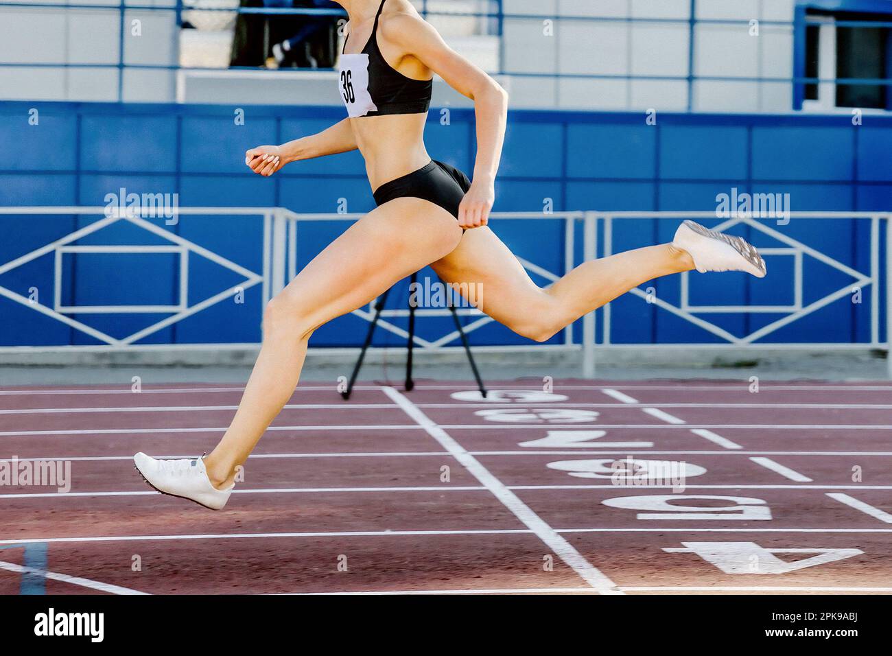 female leader runner crosses finish line on stadium track, sprint race in athletics competition Stock Photo