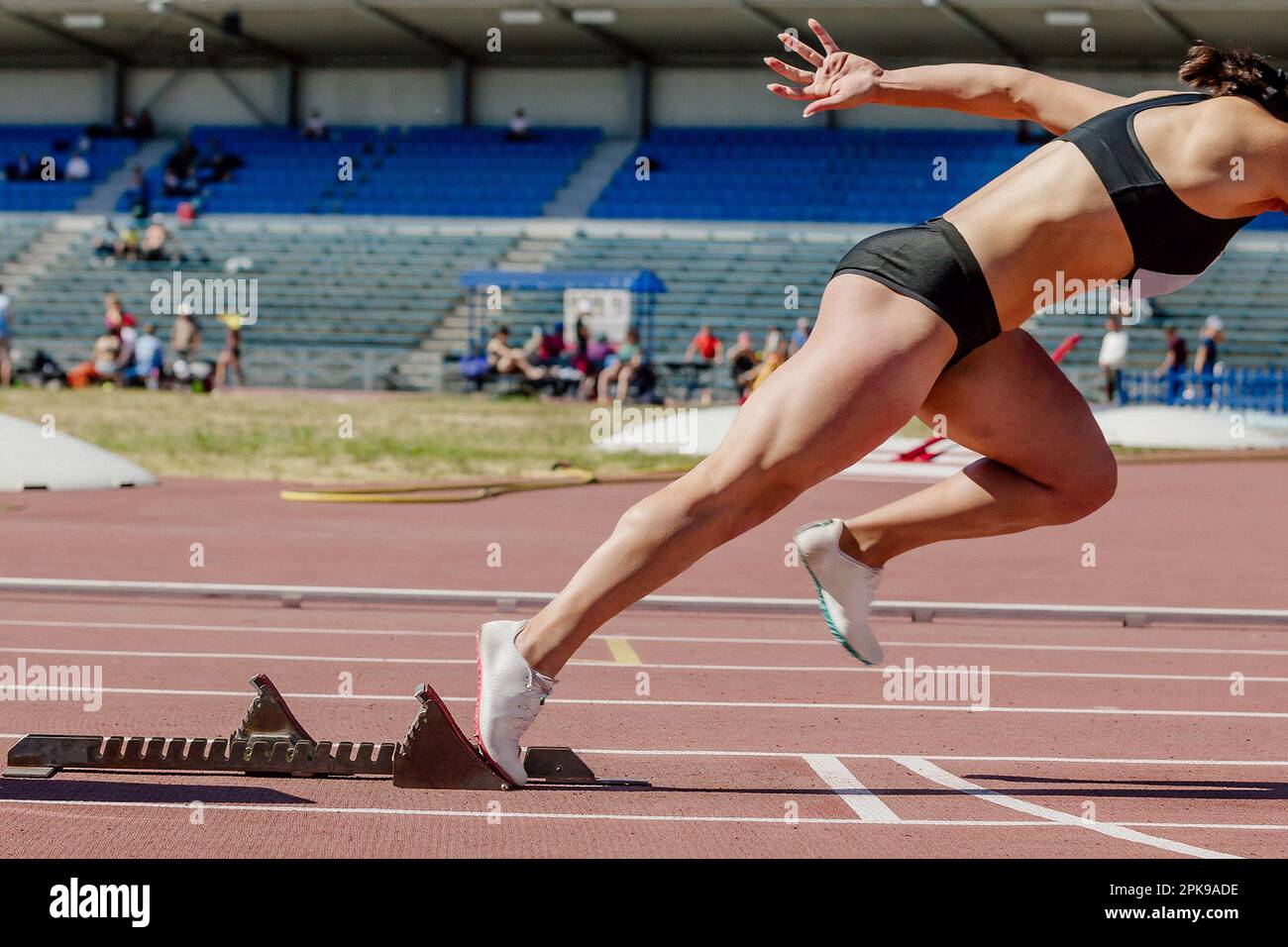 female sprinter start running from starting blocks running on stadium
