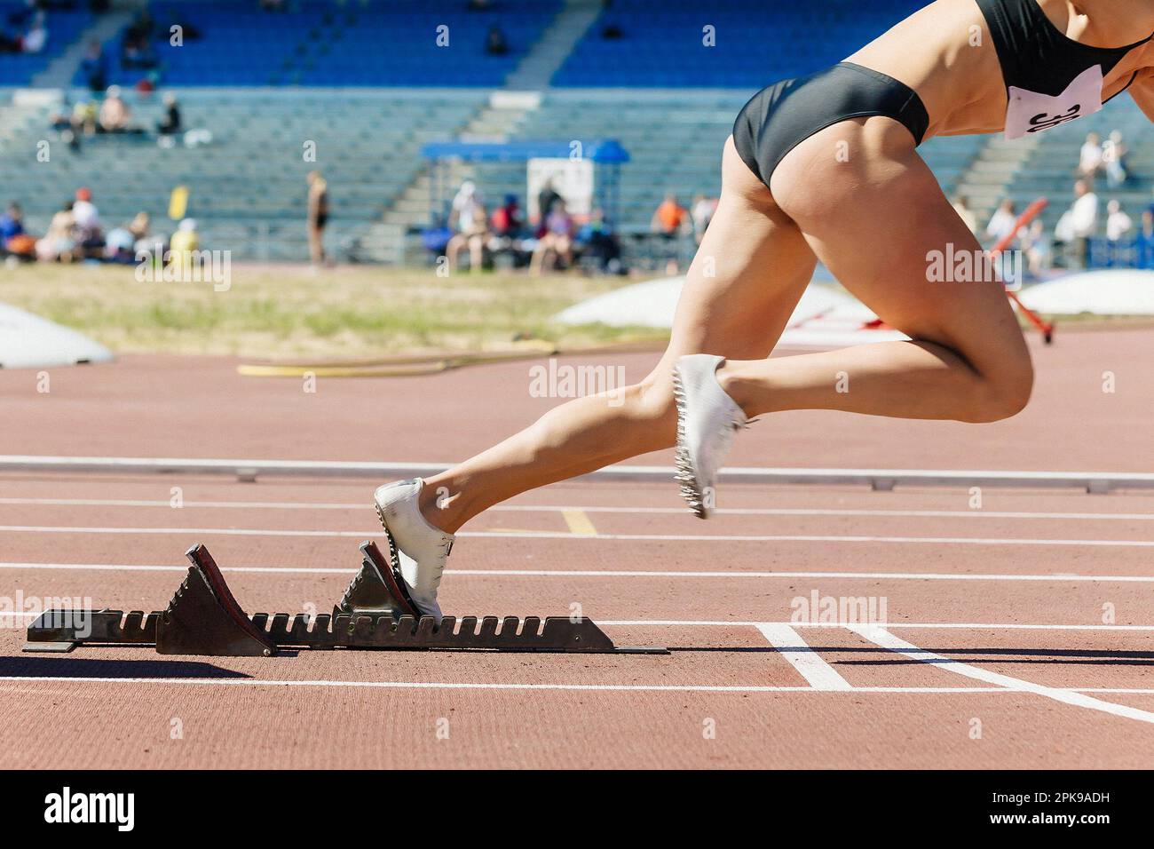 closeup female sprinter start from starting blocks run on stadium track, summer athletics