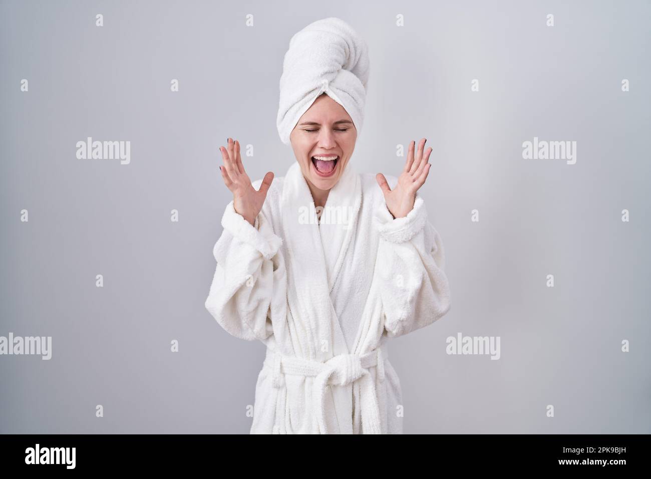 Blonde caucasian woman wearing bathrobe celebrating mad and crazy for
