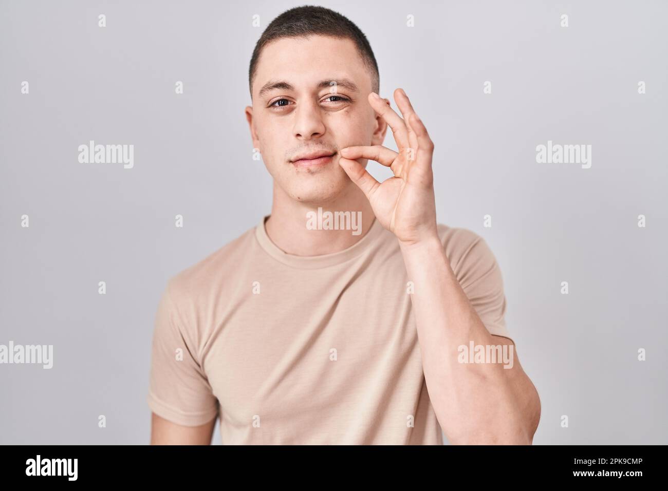 Young man standing over isolated background mouth and lips shut as zip ...