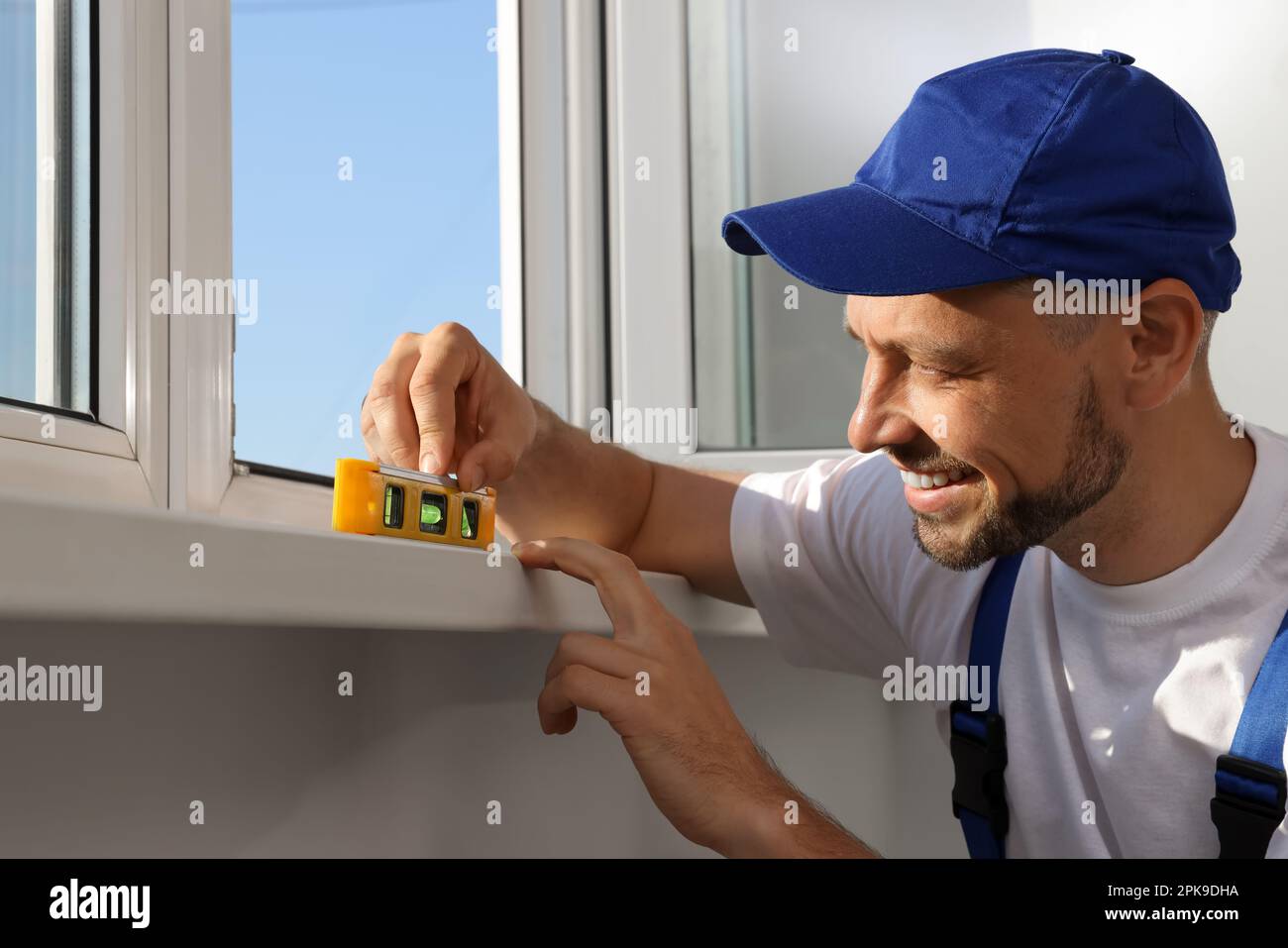 Worker using bubble level after plastic window installation indoors Stock Photo