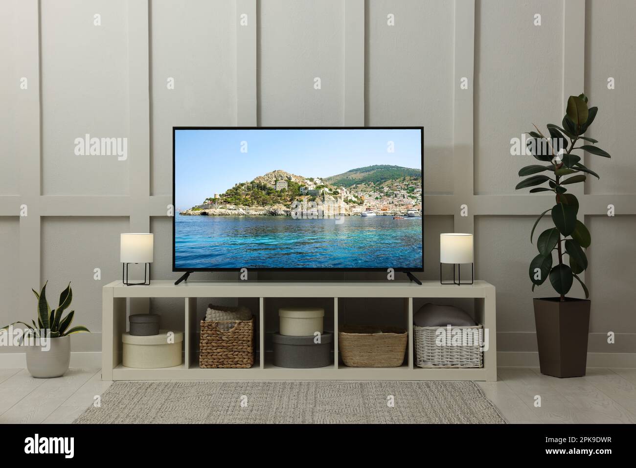 Modern TV set on wooden stand in room. Scene of nature themed movie on screen Stock Photo