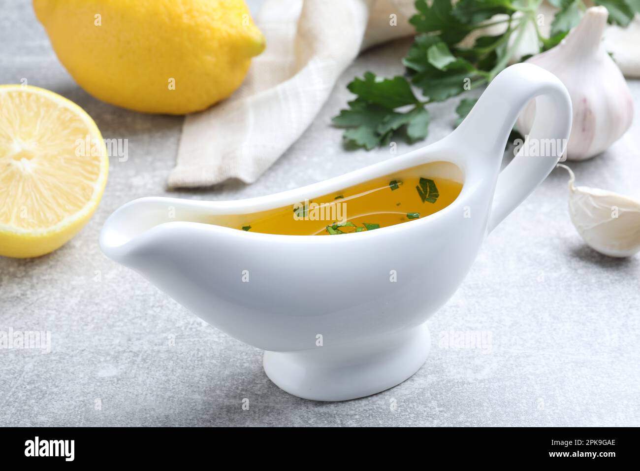 Ceramic boat with lemon sauce on light table, closeup. Delicious salad dressing Stock Photo Alamy