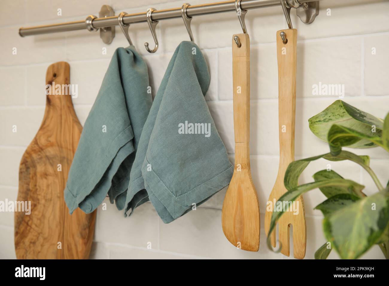 Clean towels and utensils hanging on rack in kitchen Stock Photo - Alamy