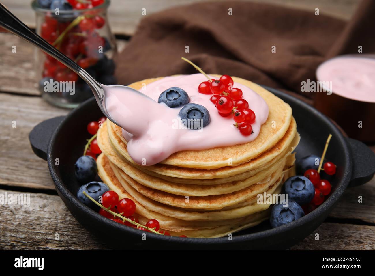 Tasty pancakes with natural yogurt, blueberries and red currants on wooden table Stock Photo